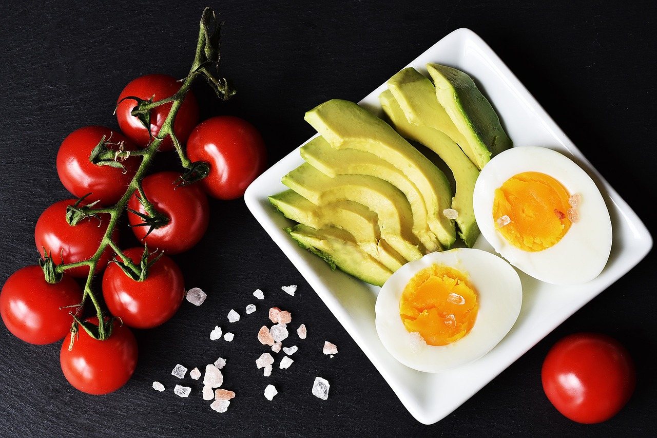 Sliced avocado, boiled eggs and vine tomatoes on a dark slate